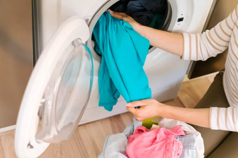 Osoba vloží bielizeň do práčky